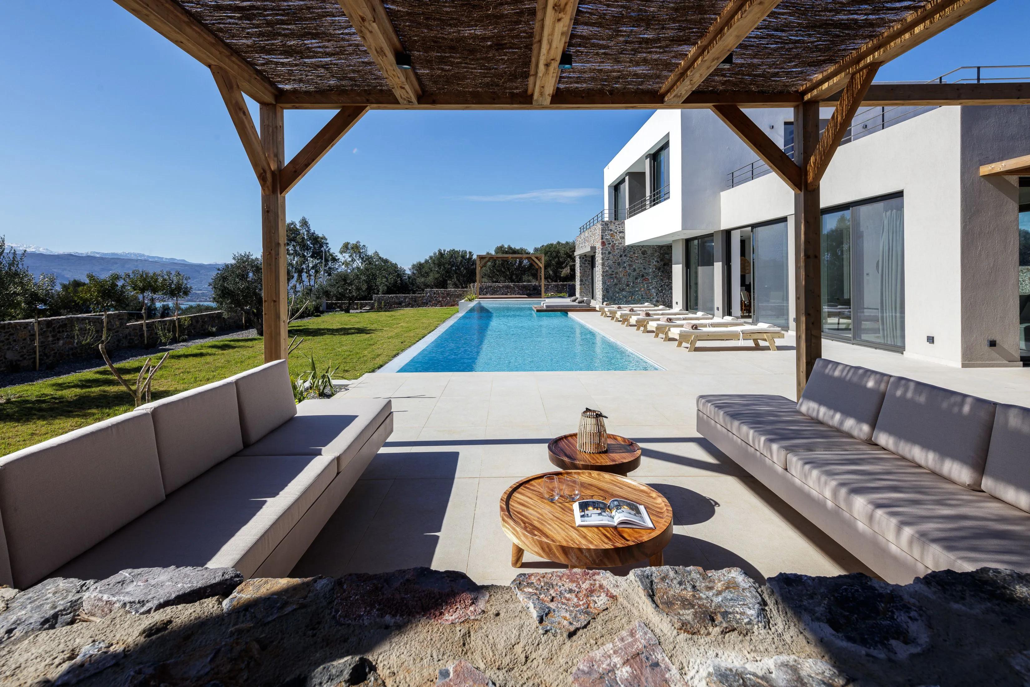 The outdoor seating area under a pergola is a firm base for poolside drinks!