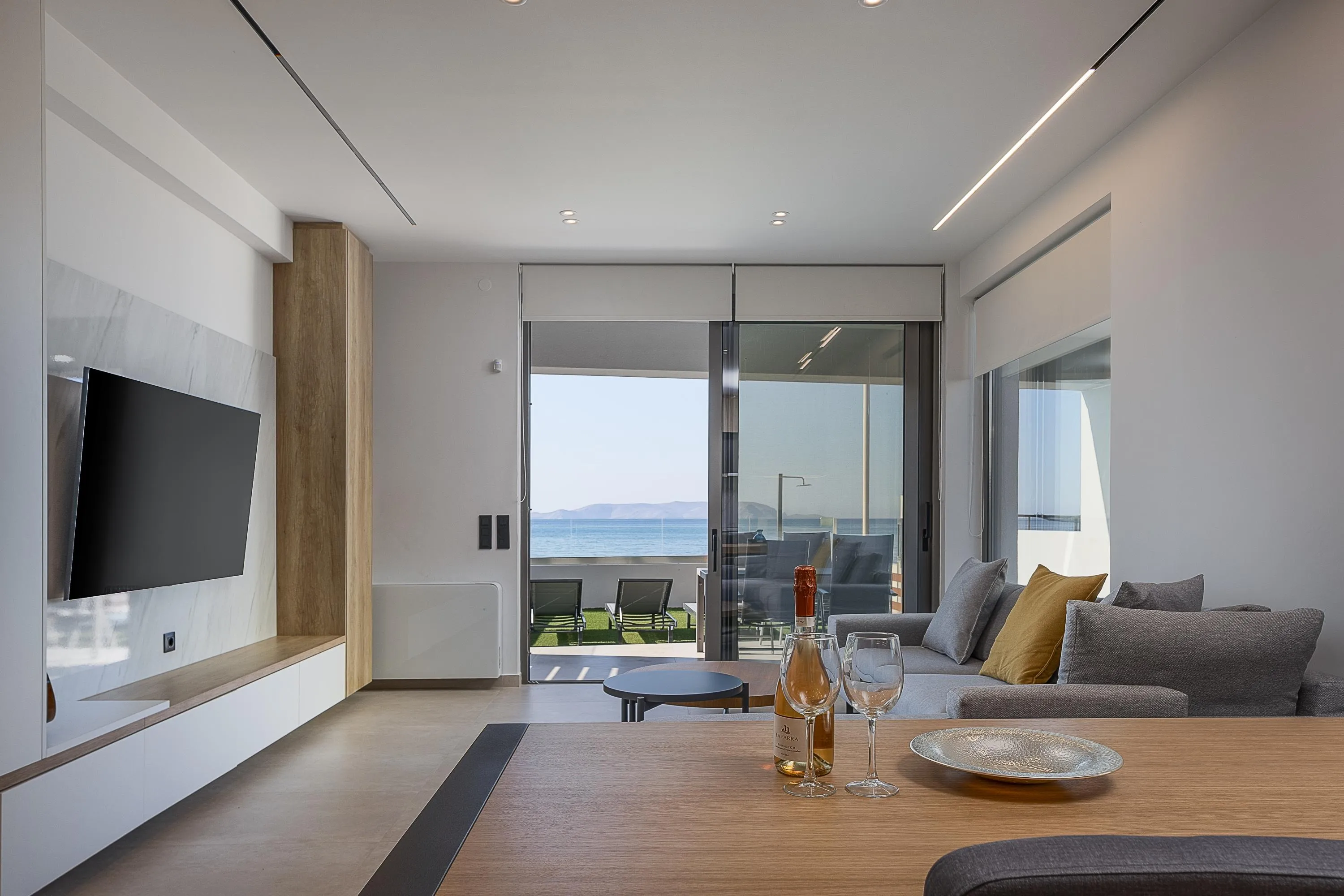 The living room includes a 65” LG TV and a spacious corner sofa, while the fully equipped kitchen offers modern appliances and an island with seating for four.