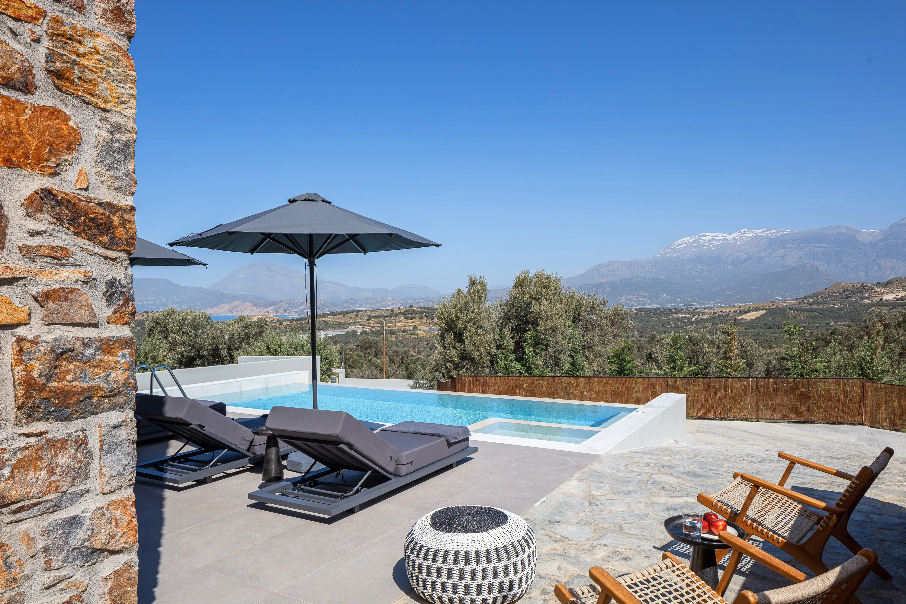 The pool area is equipped with sun beds, side tables, a poolside shower and umbrellas