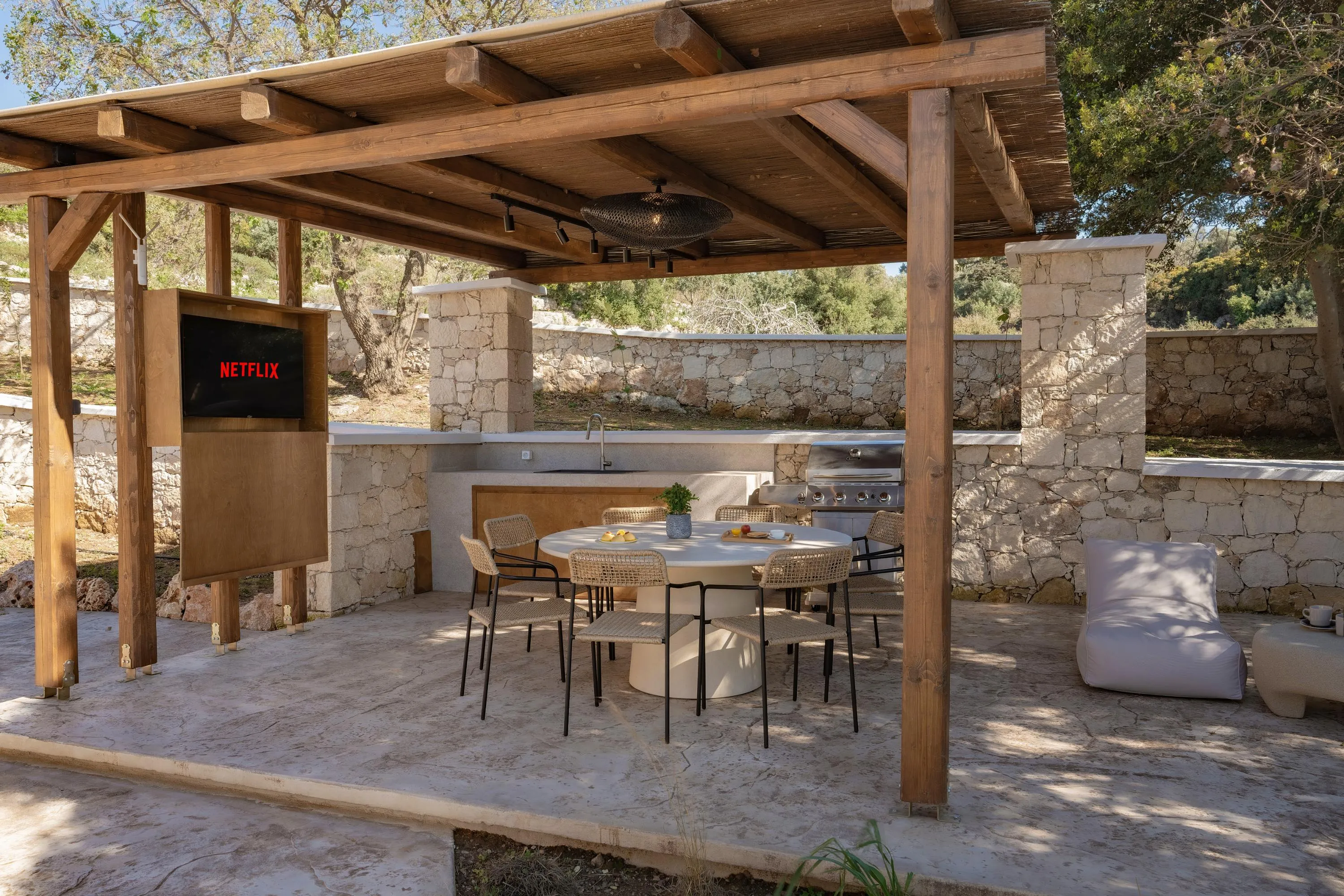 BBQ area featuring a NATTERA gas BBQ grill, a sink, a 43” TV, under a shaded pergola.