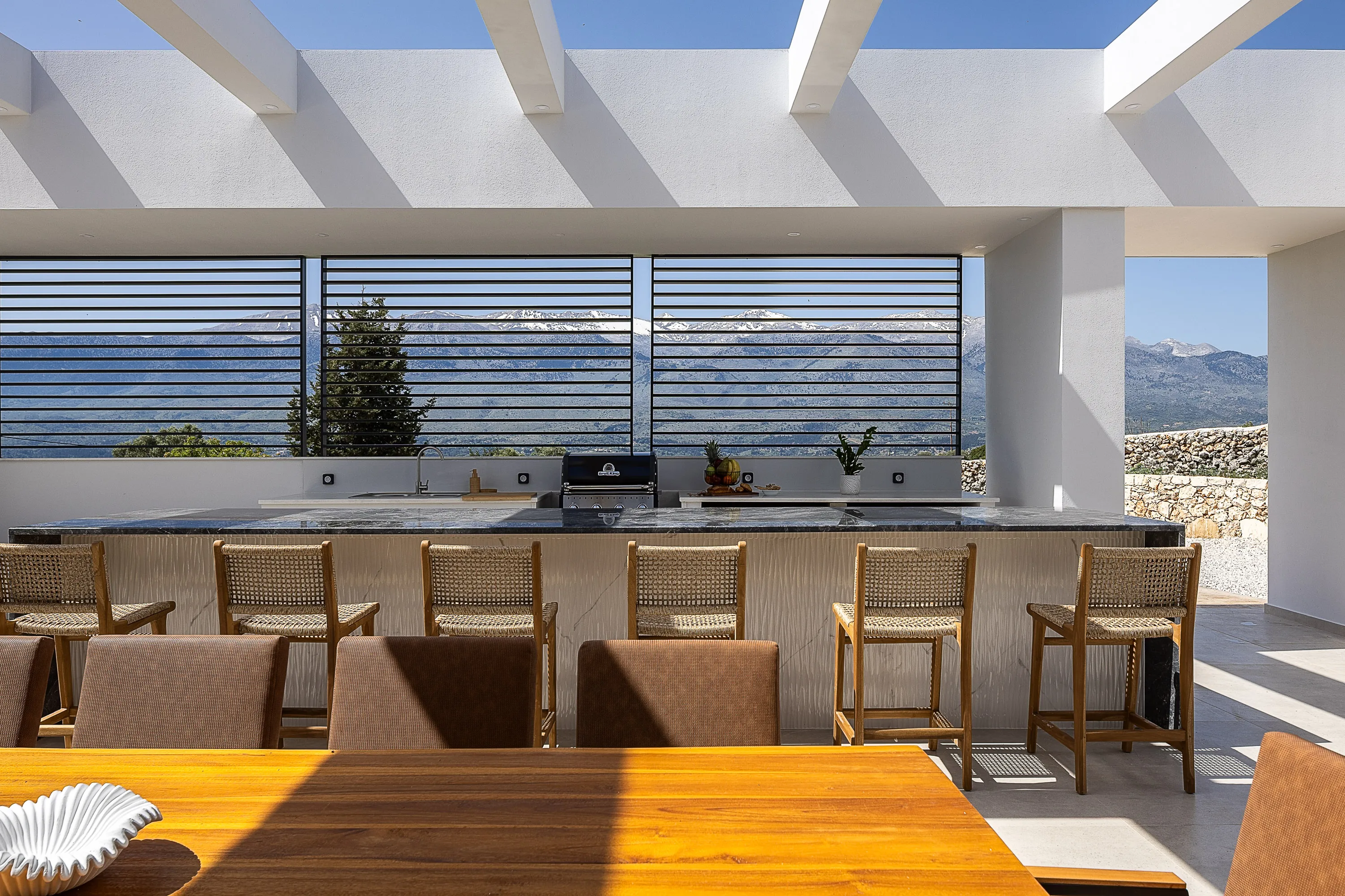 Οutdoor dining area for 10 guests under a shaded pergola.