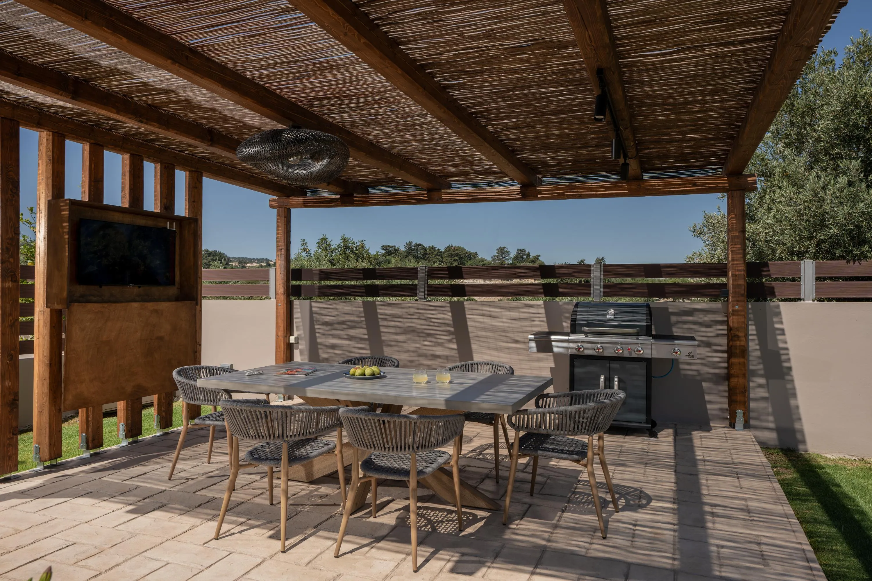 Wooden pergola with gas BBQ and dining area for 6 guests.