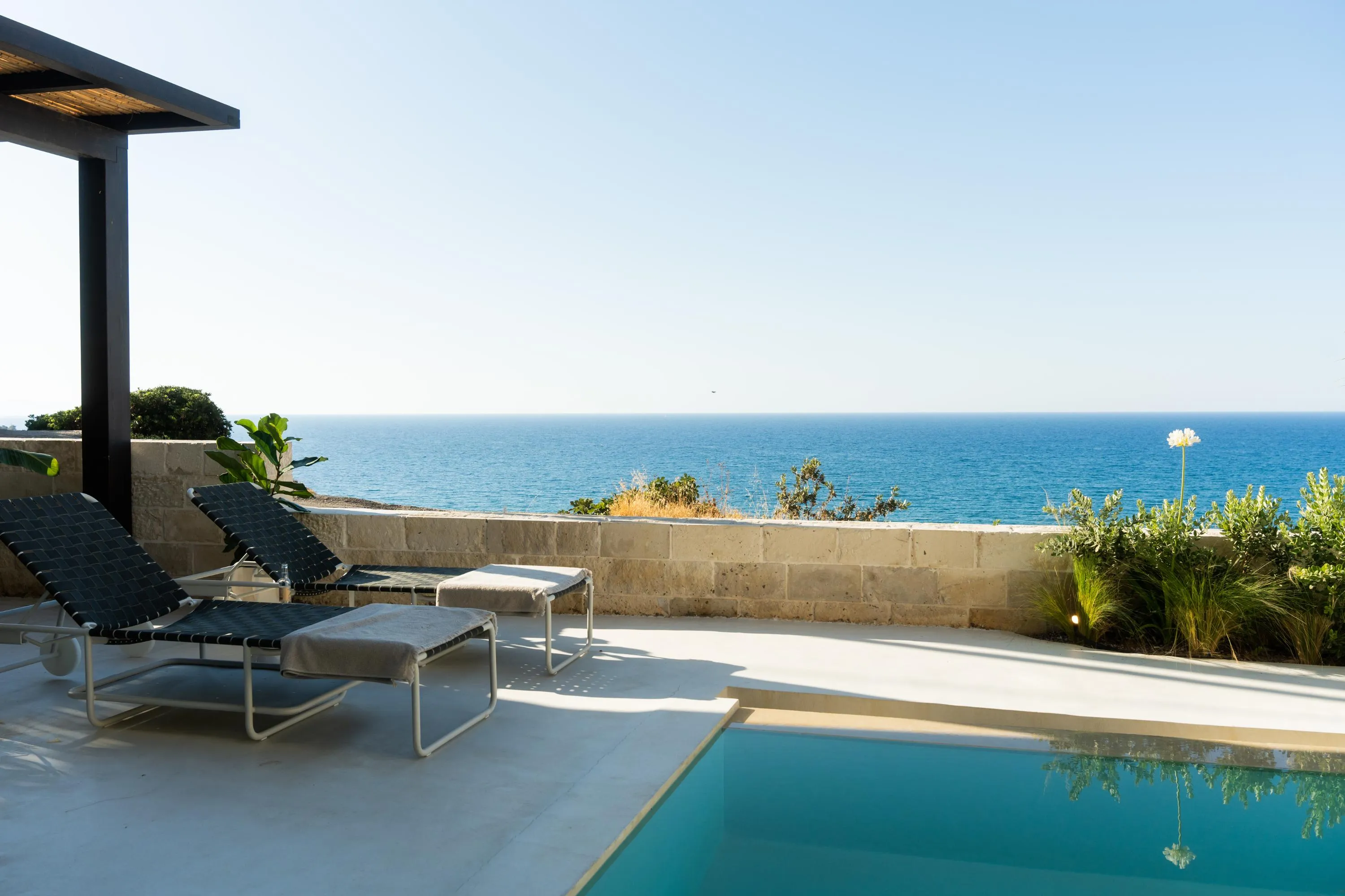 This area also features Paola Lenti pouf loungers, sunbeds, a shaded pergola, and an outdoor shower.