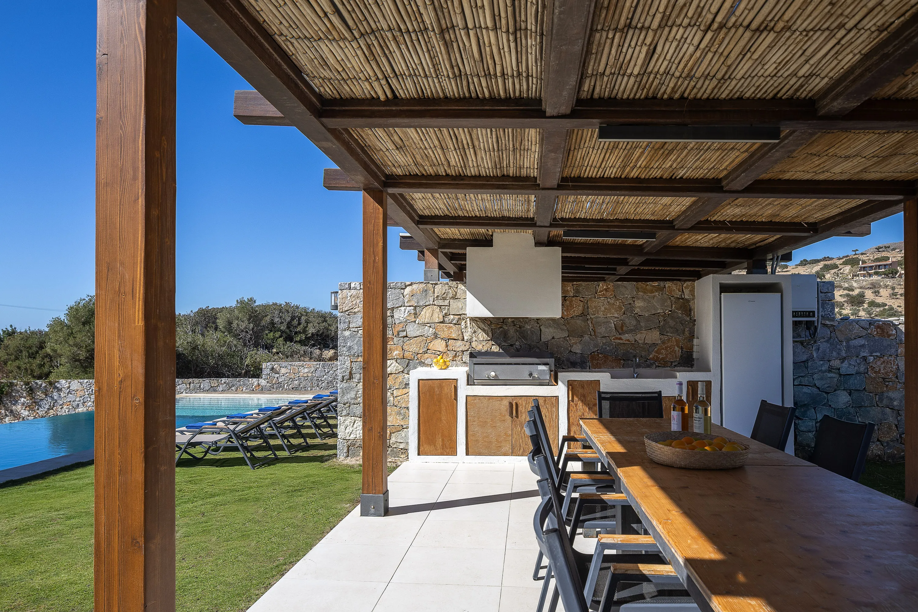 Outdoor kitchen, gas barbecue & large outdoor dining table by pool area