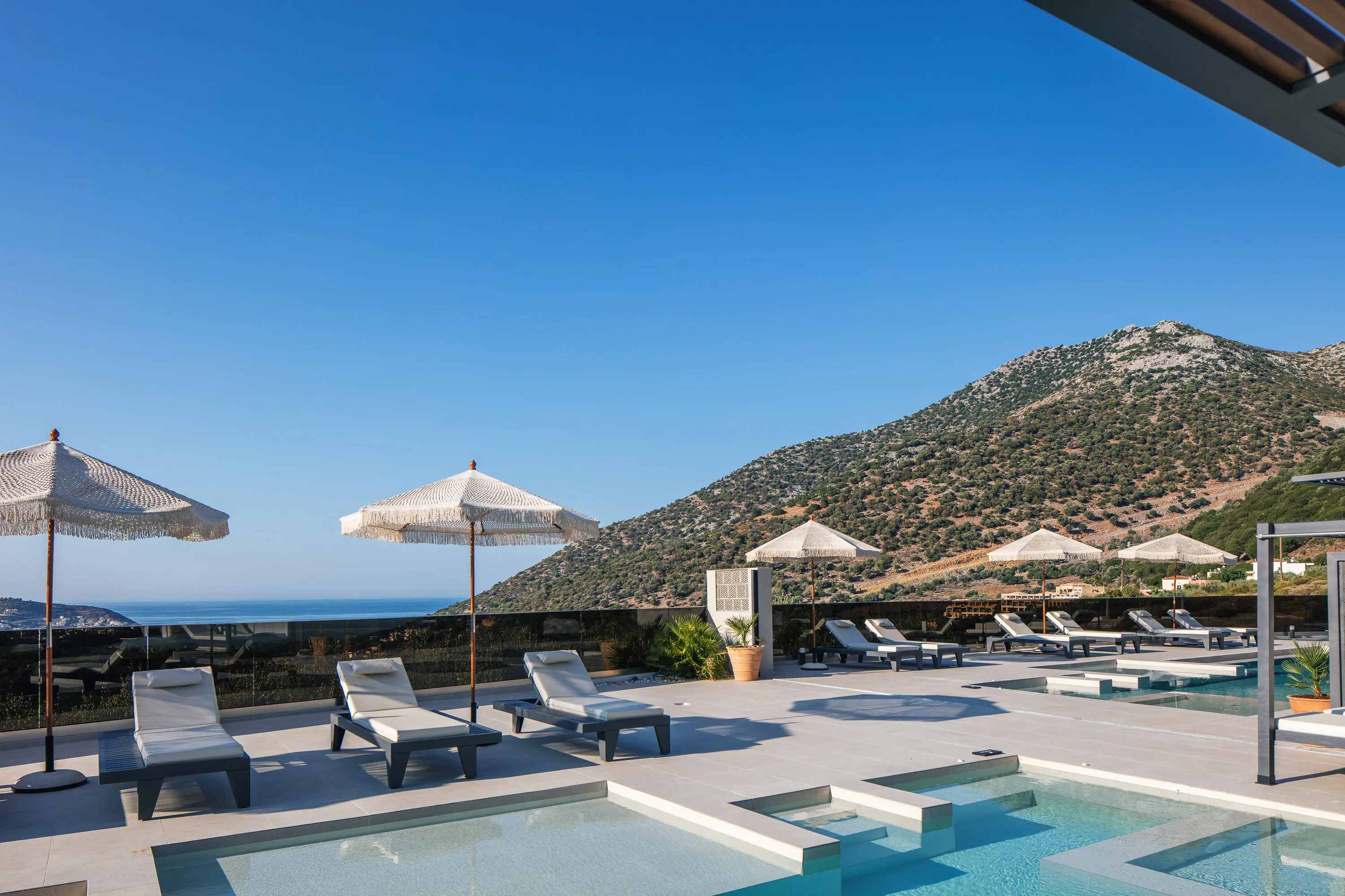 The pool areas are equipped, with 12 sun beds, accompanied by side tables, 4 cozy bean bag chairs, 8 umbrellas, and two hot water-equipped poolside showers
