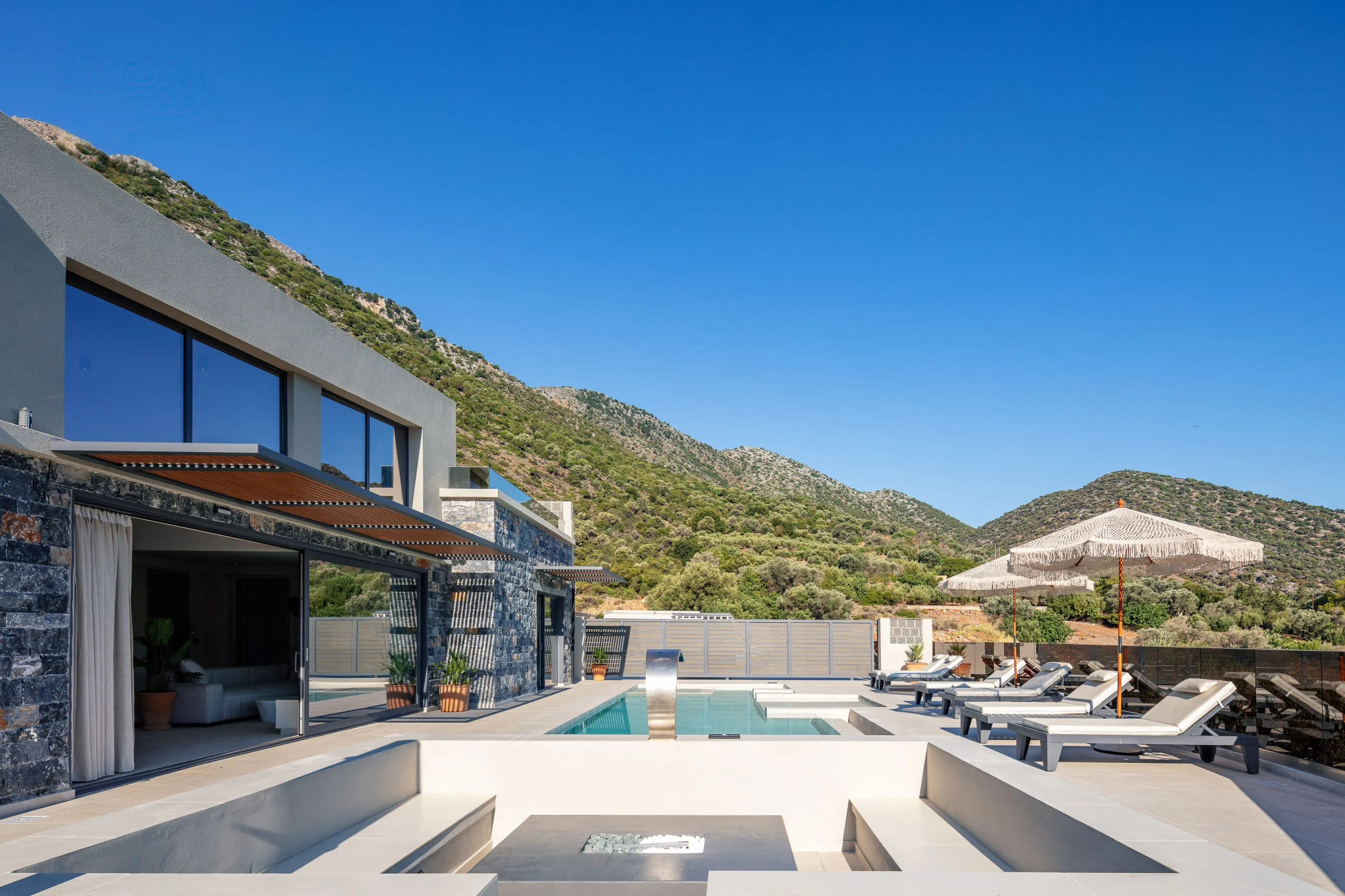 A private, 56 sq.m. swimming pool, adorned with a graceful waterfall and two in-pool chaise longues.