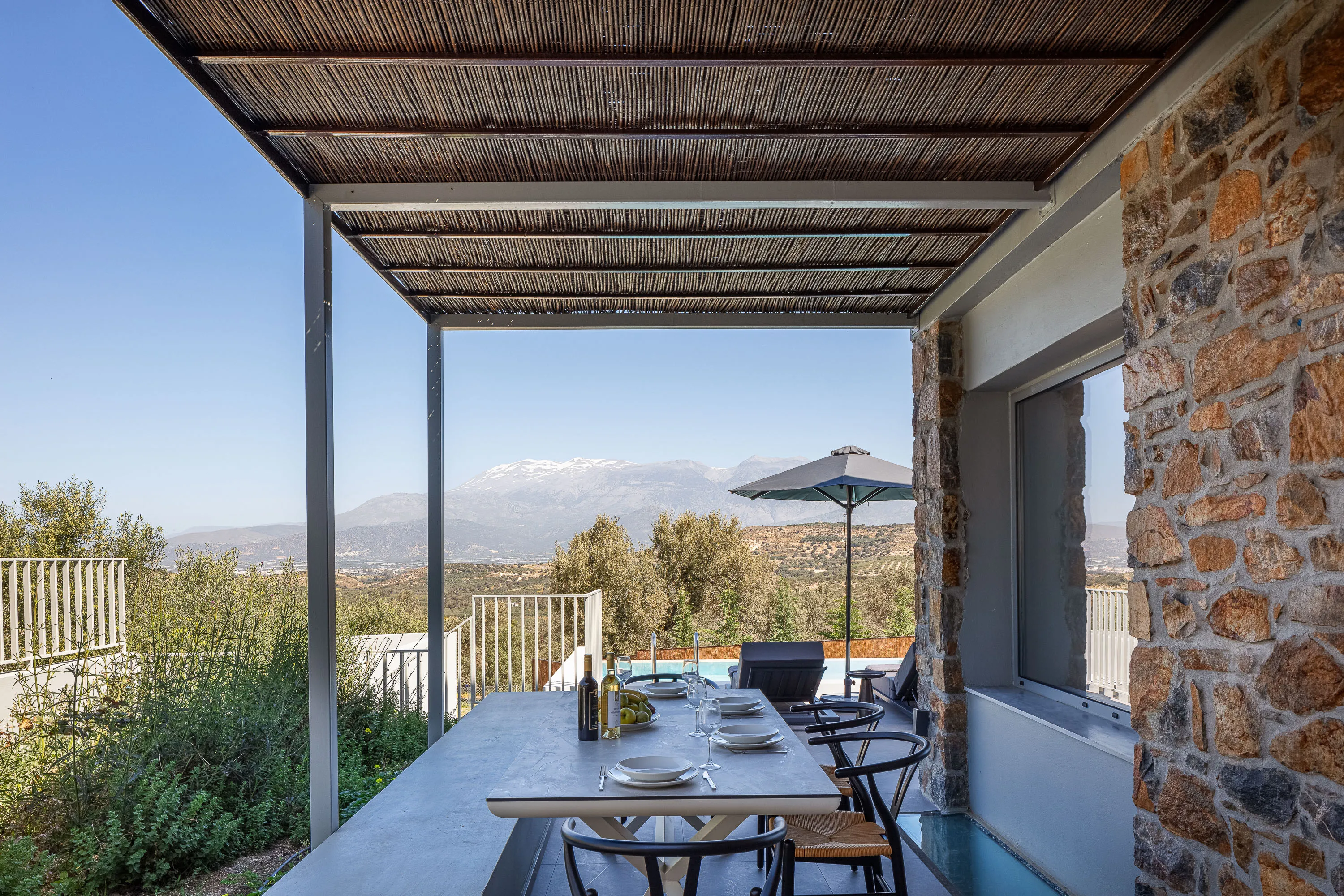 Οutdoor dining area for 8 guests under a shaded pergola